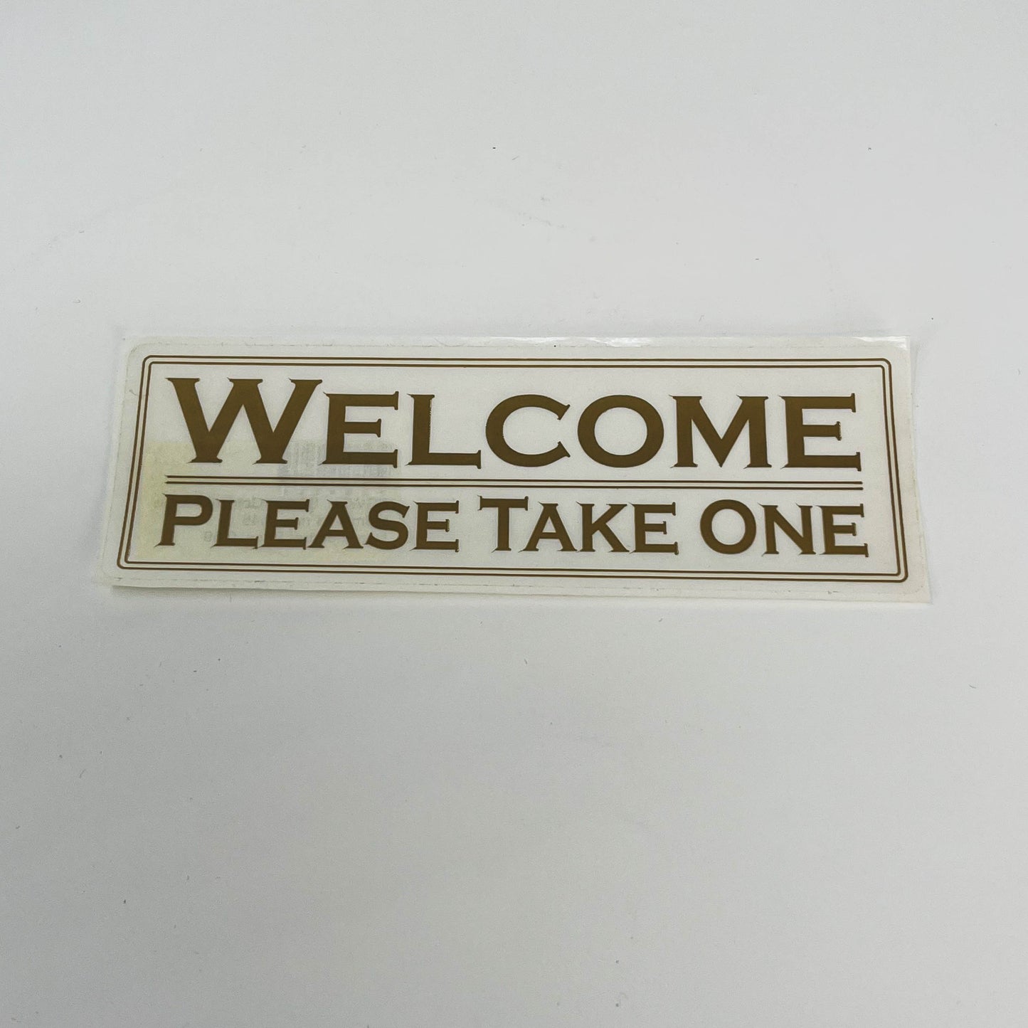 Sticker Welcome Please Take One white with gold letters  2"x 6"  (SGWEL)